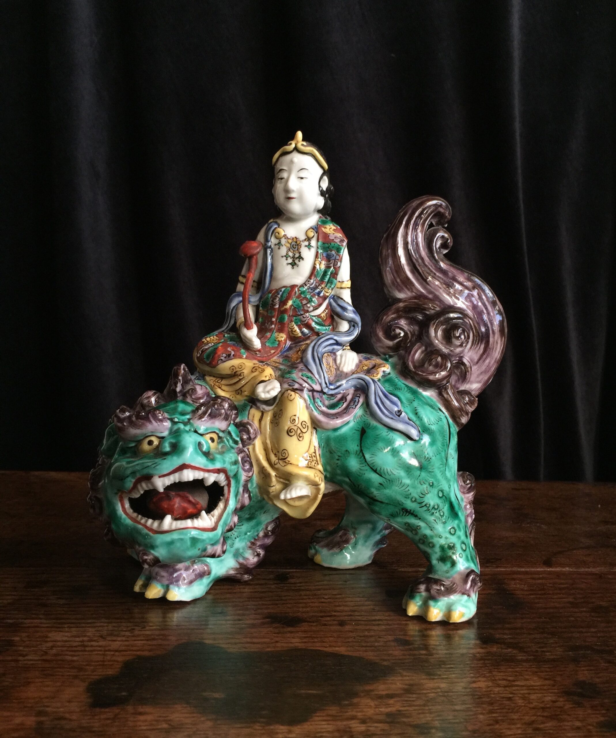 Japanese porcelain figure of Kannon (Guanyin) on a shishi (Foo dog), in famille verte colours, c.1890-0