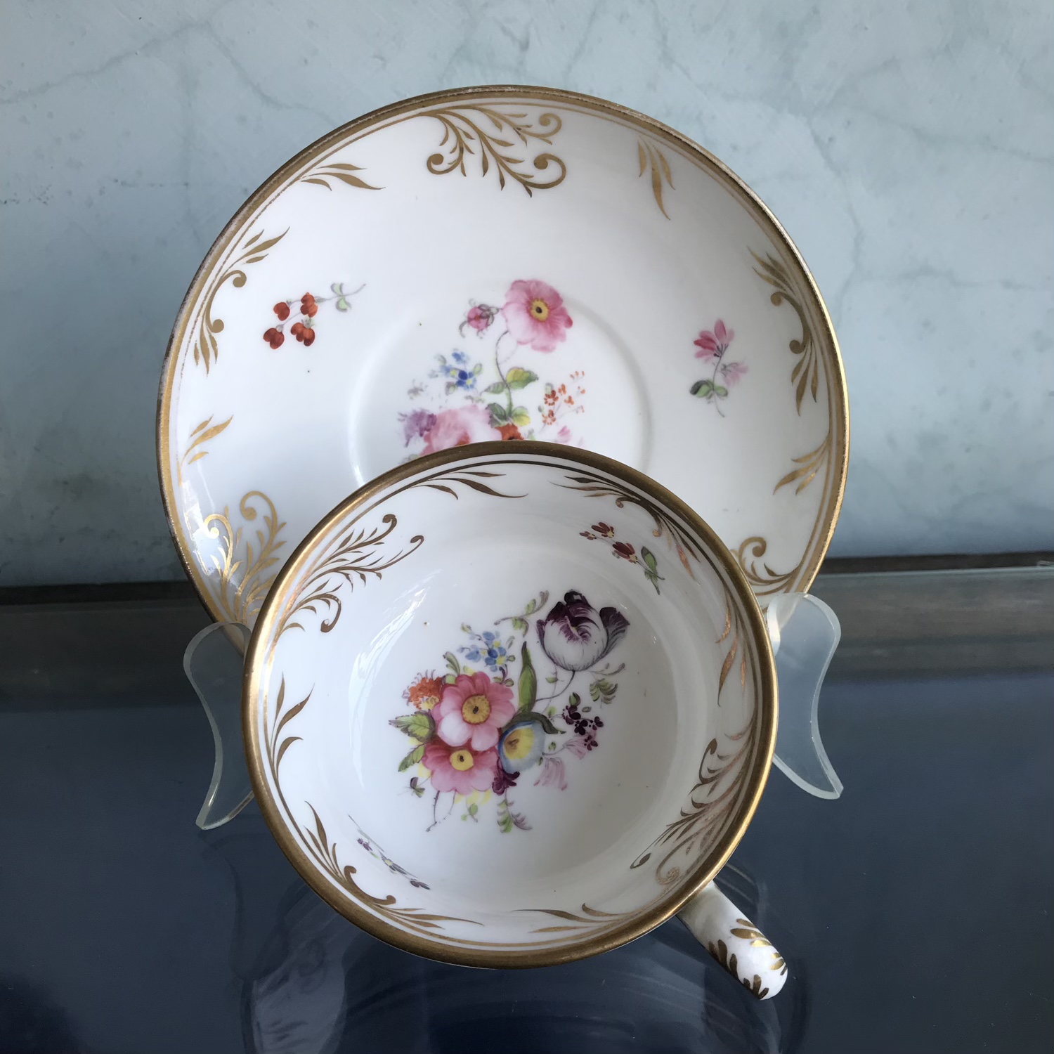 Minton french shape cup and saucer with painted flowers and gilt vine rims, c.1835