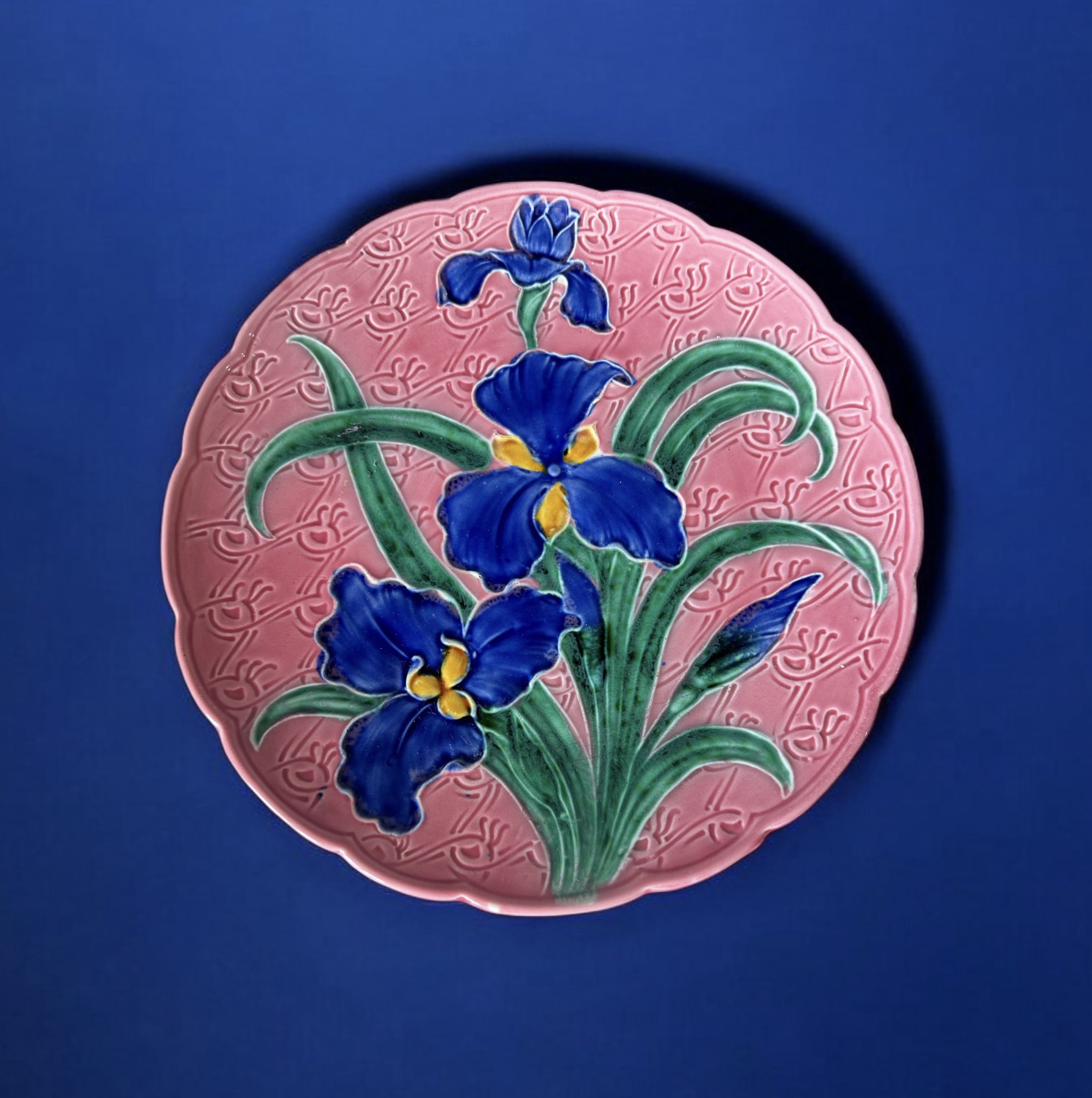 Colourful French Majolica charger, moulded + painted with iris flowers on a pink patterned ground, by Grünstadt, c. 1890